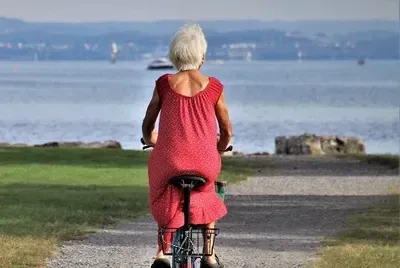 Elderly woman cycling outdoors by the water